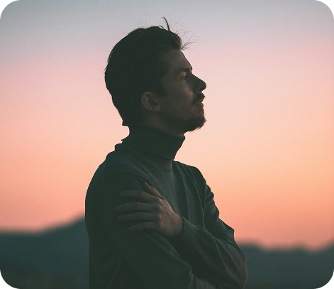 Man in profile looking toward a warm sunset